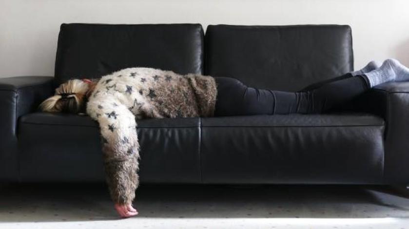 A woman with long COVID fatigue sprawled out on a couch