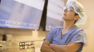 Doctor wearing scrubs looks up at screen